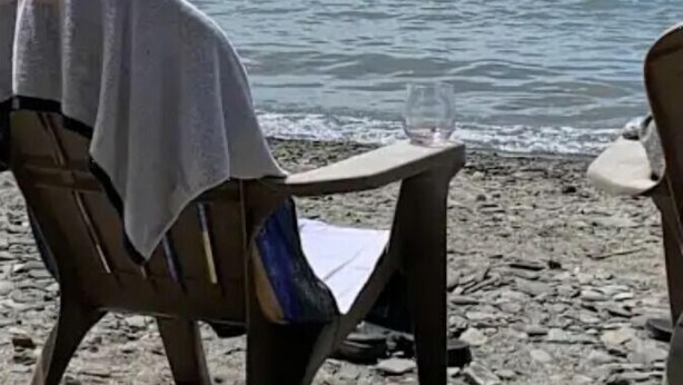A beach with a chair and a table, both covered with a white cloth. - Lake Erie Lily Cabin (Fredonia)