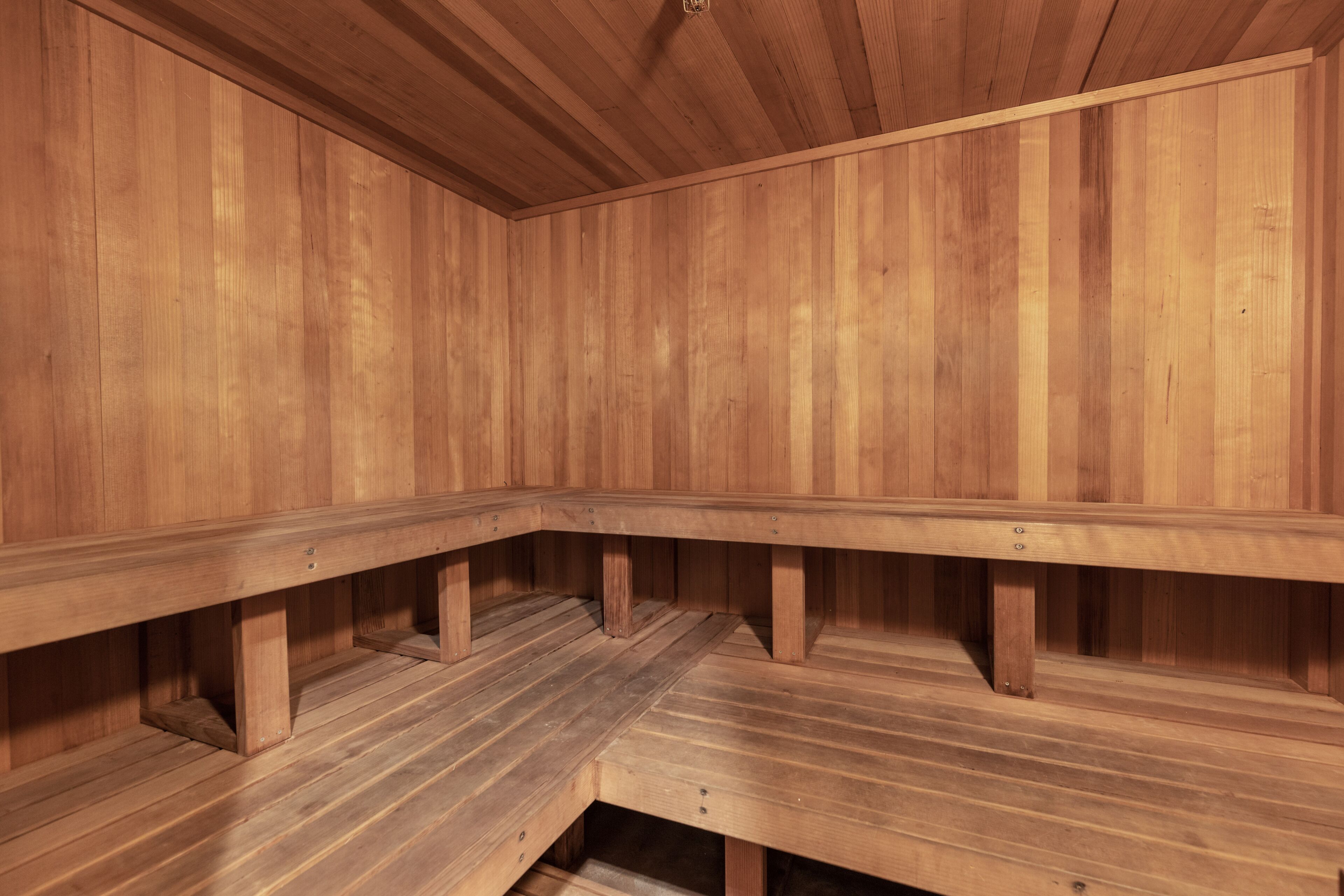 A wooden sauna with benches and a sloped floor.