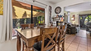 A dining area with a wooden table and chairs, a large window with blinds, and a view of trees outside. - Recently acquired property that's a work in progress (Sedona)