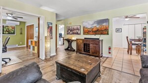 A spacious living room with a wooden coffee table, a dining area with a table and chairs, and a kitchen in the background. - Recently acquired property that's a work in progress (Sedona)