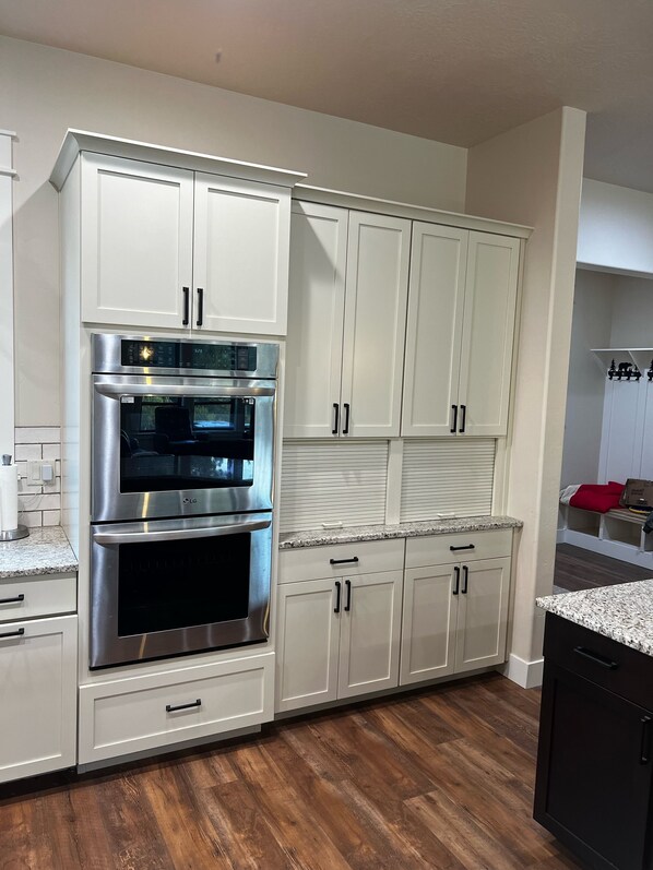 A kitchen with white cabinets, a stainless steel oven, and a granite countertop.