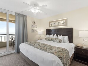 A hotel room with a bed, a nightstand, a lamp, a phone, a ceiling fan, a view of the ocean, and a balcony with chairs. - 14TH FLOOR OCEANVIEW CONDO|SHORT WALK TO THE BEACH UNIT 1408|ACCESS TO AMMENTIES (North Myrtle Beach)