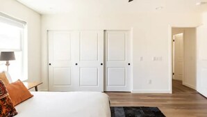 A bedroom with a bed, a nightstand, a lamp, and a black rug. - New Raven Ranch-Dreamy Compound With Spa, Hammock Circle, Yoga Platforms, & More (Yucca Valley)
