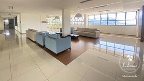 Un salón moderno y espacioso con un amplio ventanal que ofrece vistas a la ciudad, un conjunto de sofás y una mesa de centro.