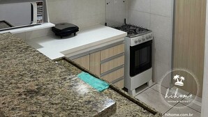Una cocina con armarios de madera, microondas, estufa a gas y encimeras de granito.