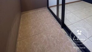 Un balcón con vista a la ciudad, puerta de cristal y suelo de baldosas.