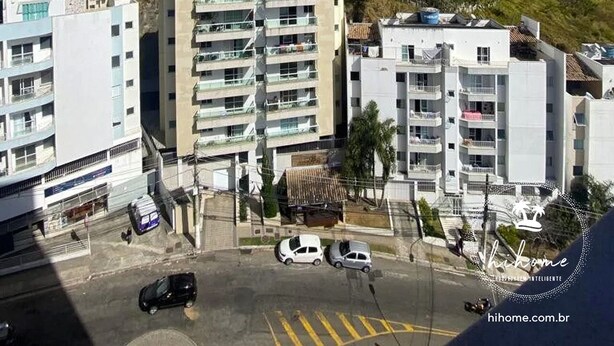 Un edificio alto con varios pisos, rodeado de otros edificios y un paisaje montañoso.