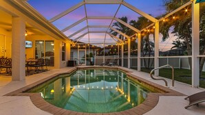 Piscina coperta con luci a stringa, poltrone relax e area solarium.
