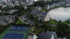 A residential area with houses, a tennis court, and a lake. - 3BR/Game Room/Pool/Outdoor Sports/3 miles to DE and MD Beaches (Selbyville)