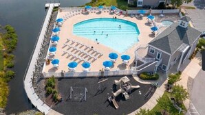 An aerial view of a swimming pool area with lounge chairs and umbrellas, surrounded by a deck and a house. - 3BR/Game Room/Pool/Outdoor Sports/3 miles to DE and MD Beaches (Selbyville)