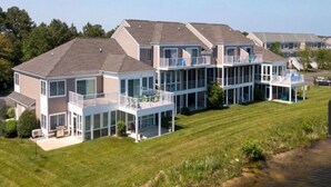 A modern multi-story house with large glass windows, a covered patio, and a well-maintained lawn. - 3BR/Game Room/Pool/Outdoor Sports/3 miles to DE and MD Beaches (Selbyville)