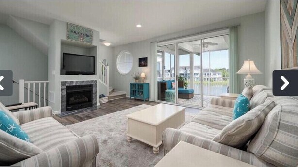 A spacious living room with a fireplace, a television, and a balcony with a view. - 3BR/Game Room/Pool/Outdoor Sports/3 miles to DE and MD Beaches (Selbyville)