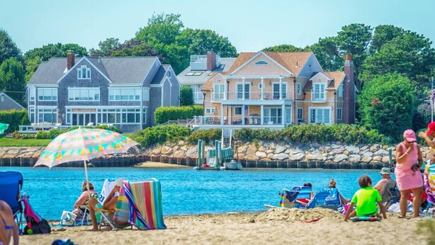 Una spiaggia con piscina, ombrelloni e persone che si rilassano.