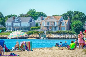 Une plage avec une piscine, des parasols et des gens qui se détendent.