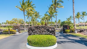 A sign with "The Geyser" written on it, surrounded by a well-maintained hedge and palm trees. - Luxury Stay w/ Private Beach Club, Hilton Pool Passes, Sunset Views (Waimea)