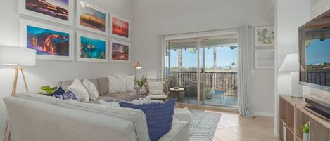Un salon spacieux avec un canapé, un téléviseur et un balcon offrant une vue agréable.