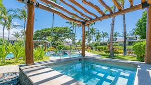 A pool area with a wooden pergola, surrounded by palm trees and a view of houses. - Luxury Stay w/ Private Beach Club, Hilton Pool Passes, Sunset Views (Waimea)