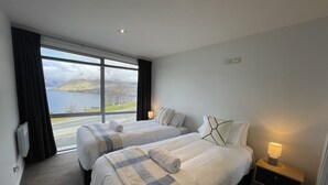 A hotel room with two beds, a view of a lake, and a small bedside table with a lamp. - Iconic Queenstown Apartment (Queenstown)