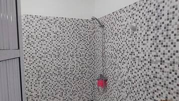 Een bad/douchecombinatie, handdoeken, zeep, toiletpapier