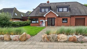 Une maison à deux étages, construite en briques, avec un toit en pente, un garage à l’avant et une pelouse bien entretenue.