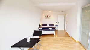 Un couloir étroit mène à une chambre qui contient un lit, une petite table et une chaise.