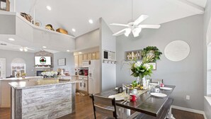 A modern kitchen with a central island, a dining area with chairs, and a ceiling fan. - Golf Course Escape • 3BR Legacy Condo w/ Fireplace & Sunroom (Branson)
