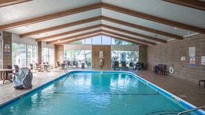 An indoor swimming pool with wooden beams, poolside chairs, and tables. - Golf Course Escape • 3BR Legacy Condo w/ Fireplace & Sunroom (Branson)