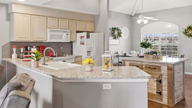 A kitchen with granite countertops, a central island, and a dining area with a view. - Golf Course Escape • 3BR Legacy Condo w/ Fireplace & Sunroom (Branson)