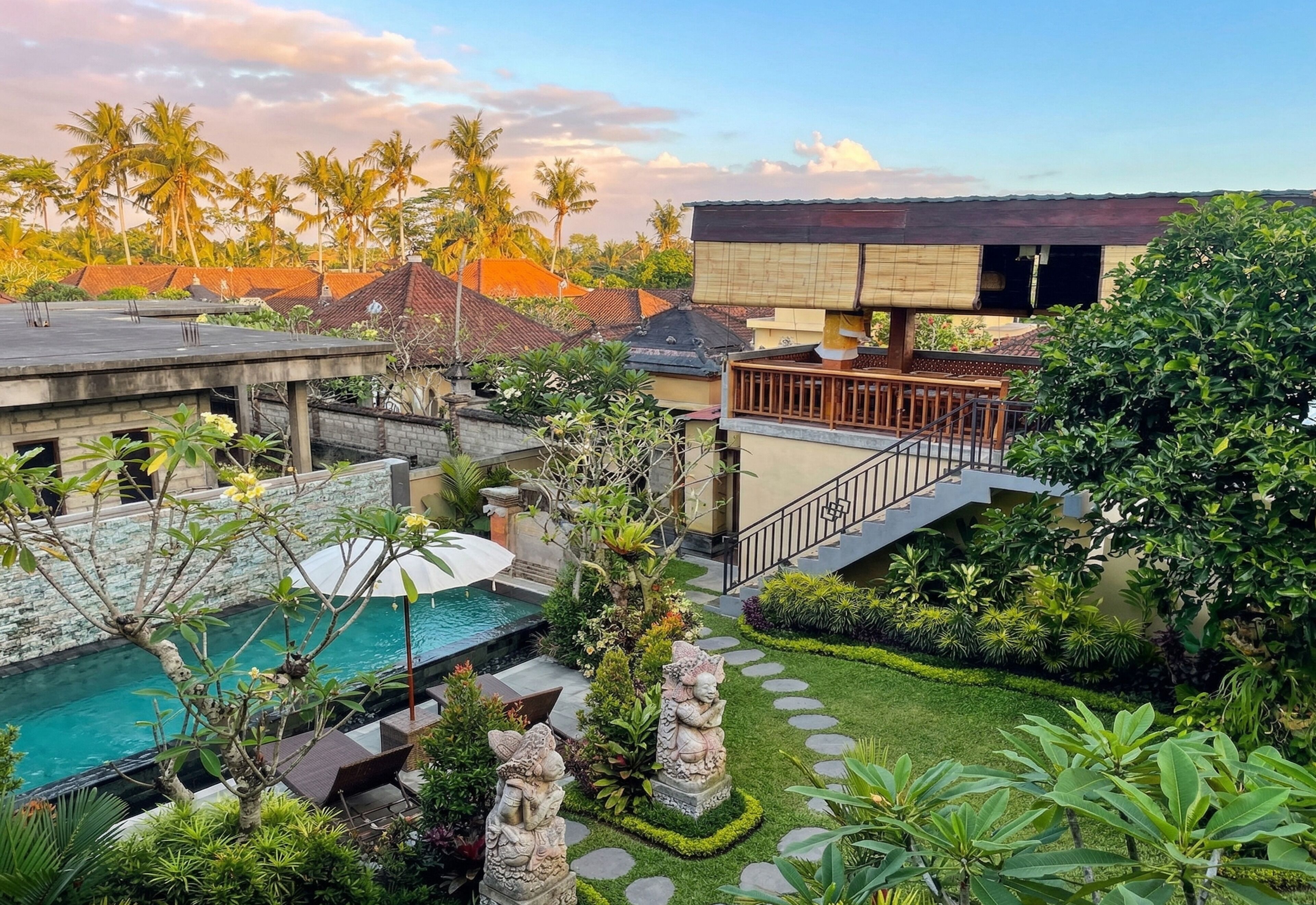 A pool area with stone statues, a staircase, and lush greenery.