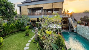 A modern house with a pool, surrounded by lush greenery and a clear sky. - Sari Murni (Ubud)