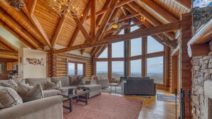 A spacious living room with a high ceiling and large windows offering a mountain view. - EPIC VIEWS-HotTub-WoodStove-Sauna-Fireplace-GameRoom-Playset-EV-FencedYard+More! (Rosman)