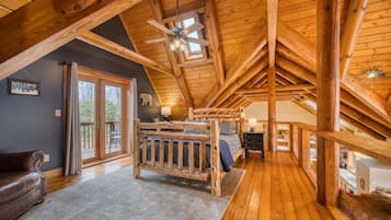 Relax in this spacious room with a high ceiling and exposed beams, featuring a large bed and comfortable leather sofa.