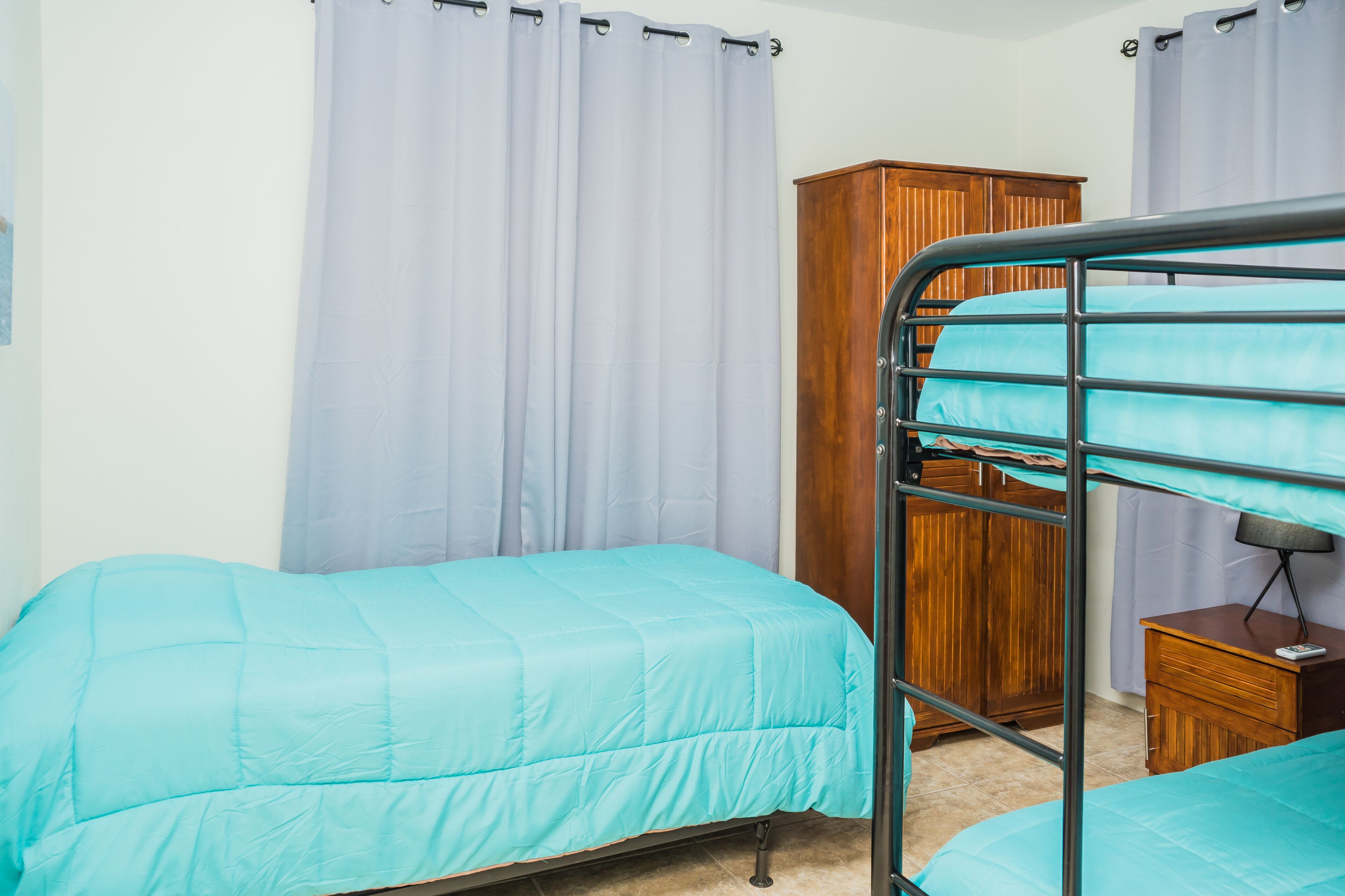 A bedroom with bunk beds, a wooden wardrobe, and a bedside table with a lamp.