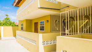 A multi-story building with a yellow facade, a gated entrance, and a balcony with decorative railings. - Aspid Studio & Apartment (Oranjestad)