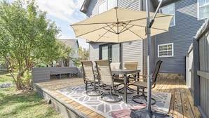 Eine Terrasse mit Tisch, Stühlen und einem Sonnenschirm, sowie ein Holzdeck.