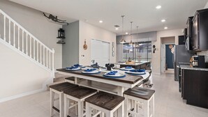 Una cocina moderna con una isla central, muebles blancos y una zona de comedor con bancos.
