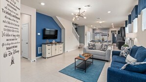 Una sala de estar moderna con una pared azul de acento, un televisor de pantalla plana, una mesa de centro y un sofá.