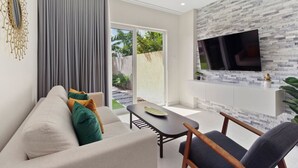 A modern living room with a grey sofa, a coffee table, and a TV mounted on a textured wall. - Aracari 6 By Bocobay (Noord)
