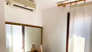 Ein Badezimmer mit Spiegel, Ablagefläche für Toilettenartikel, Duschvorhang und einem gemusterten Bettbezug.