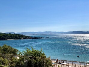 En kustvy med klar himmel, en sandstrand och klippiga utskjutande partier.