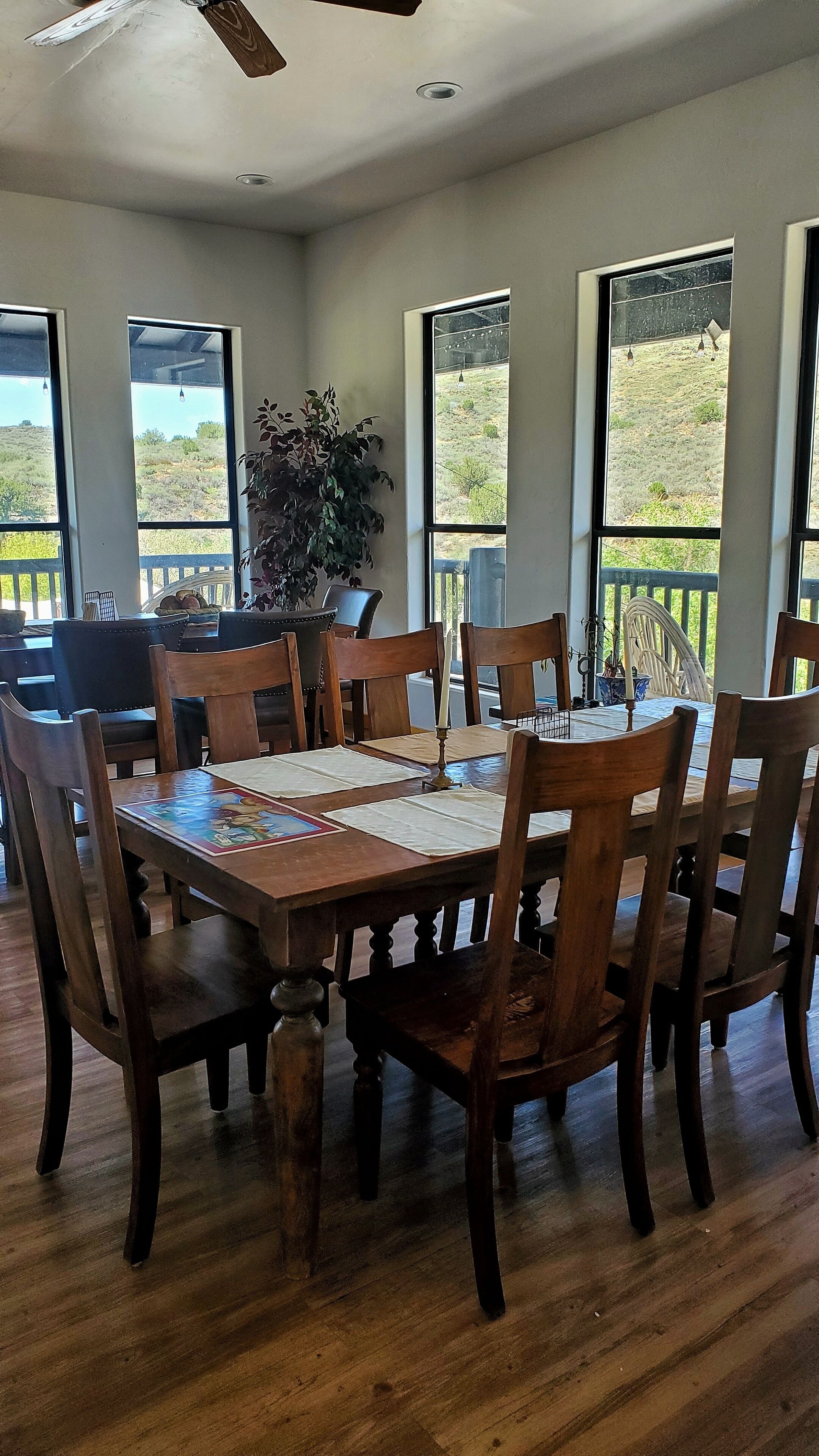 A dining area with a large table set for six, surrounded by wooden chairs.