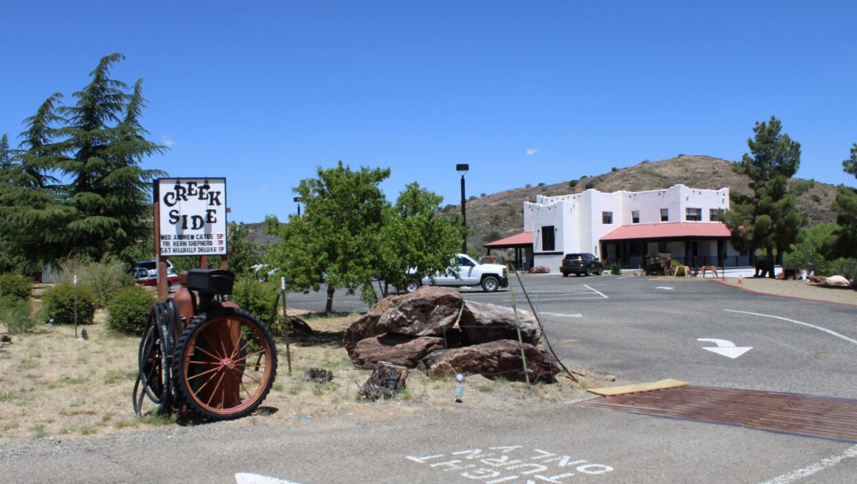 A parking lot with a sign for 'Creek Side' and a building with a red roof.