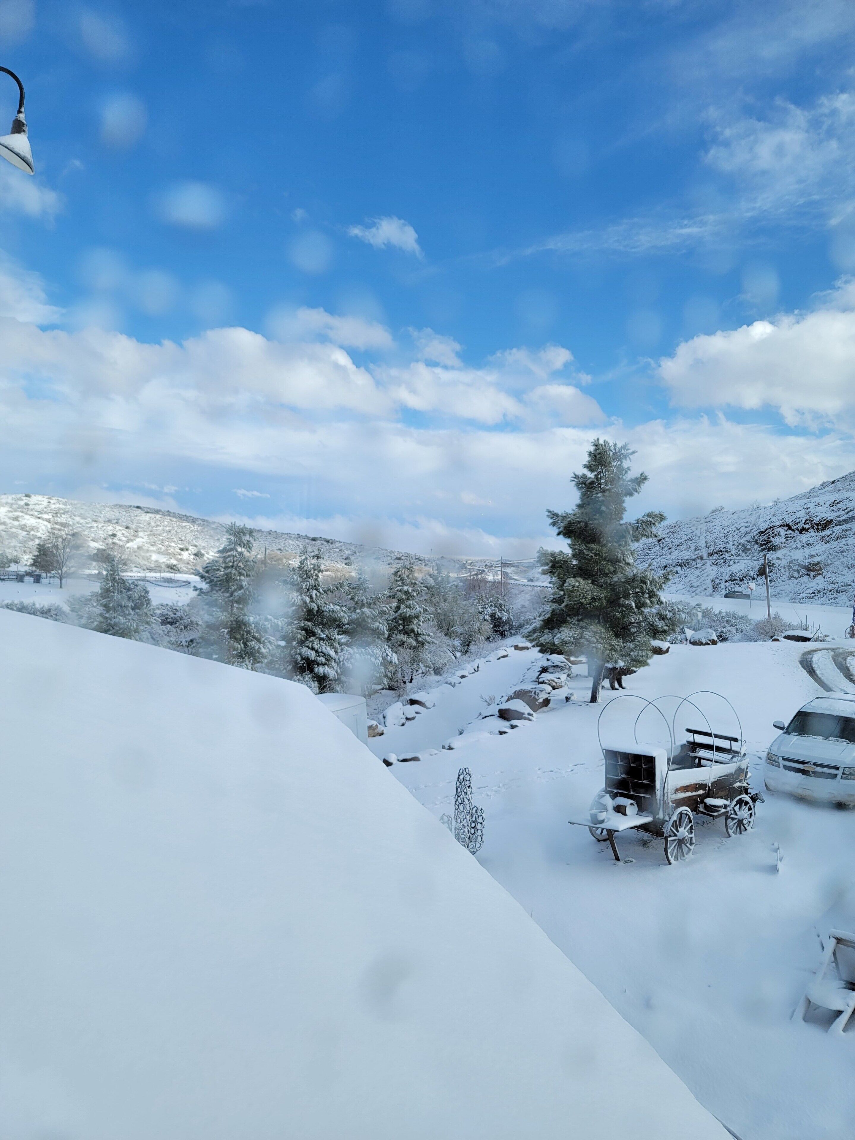 A snow-covered landscape with a clear sky, a snow-covered car, and a snow-covered wagon.