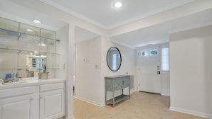 A spacious bathroom with a large vanity, a glass shower enclosure, and a round mirror. - 276 Evian: Newly renovated single story unit with golf course views and tennis court access! (Hilton Head Island)