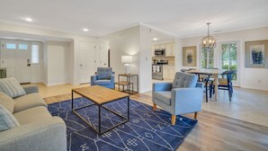 A spacious living room with a sofa, armchairs, a coffee table, and a dining area with a table and chairs. - 276 Evian: Newly renovated single story unit with golf course views and tennis court access! (Hilton Head Island)