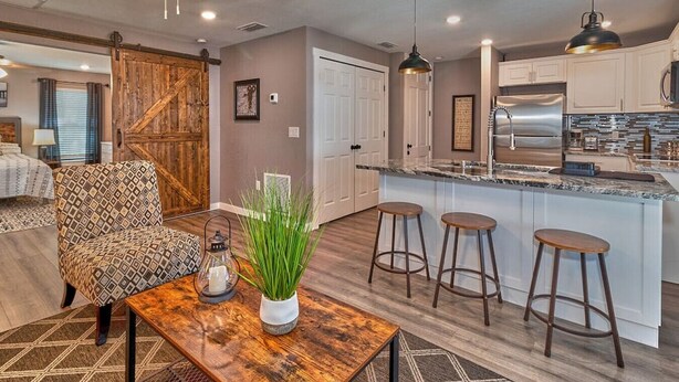 A modern kitchen with a large island, bar stools, and a rustic wooden table.