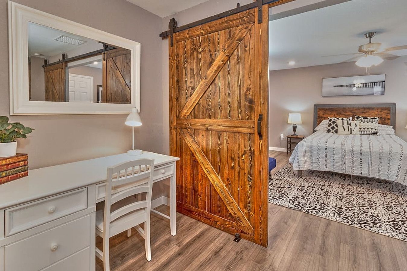 Une chambre à coucher comprenant un lit, un bureau, une chaise, une grande porte en bois et un tapis à motifs.