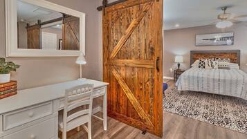 Une chambre à coucher comprenant un lit, un bureau, une chaise, une grande porte en bois et un tapis à motifs.
