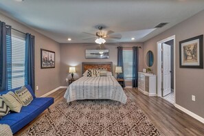 Una camera da letto con un letto, un divano blu, un tappeto decorato e una ventola a soffitto.