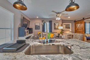 Una cocina con encimera de granito, pileta de acero inoxidable e iluminación colgante.